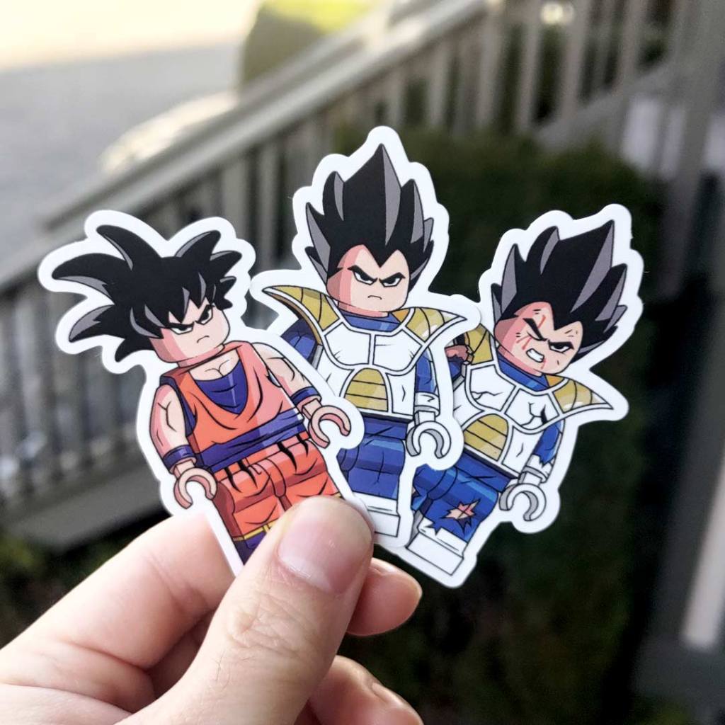 holding up stickers of lego dragon ball with goku and vegeta